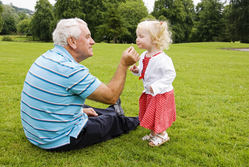 grandpa with granddaughter sitting on grass