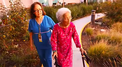 Nurse accompanying an elderly woman with a walker