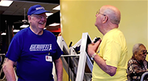 two older men exercising together at a gym