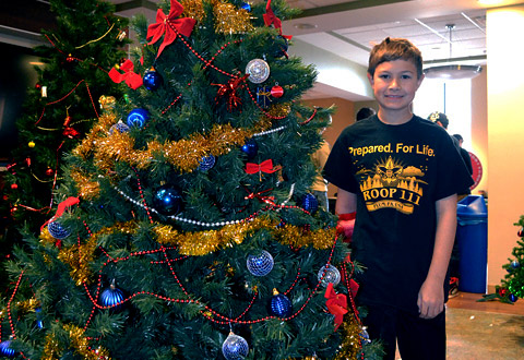 Boy scout standing next to a decorated tree