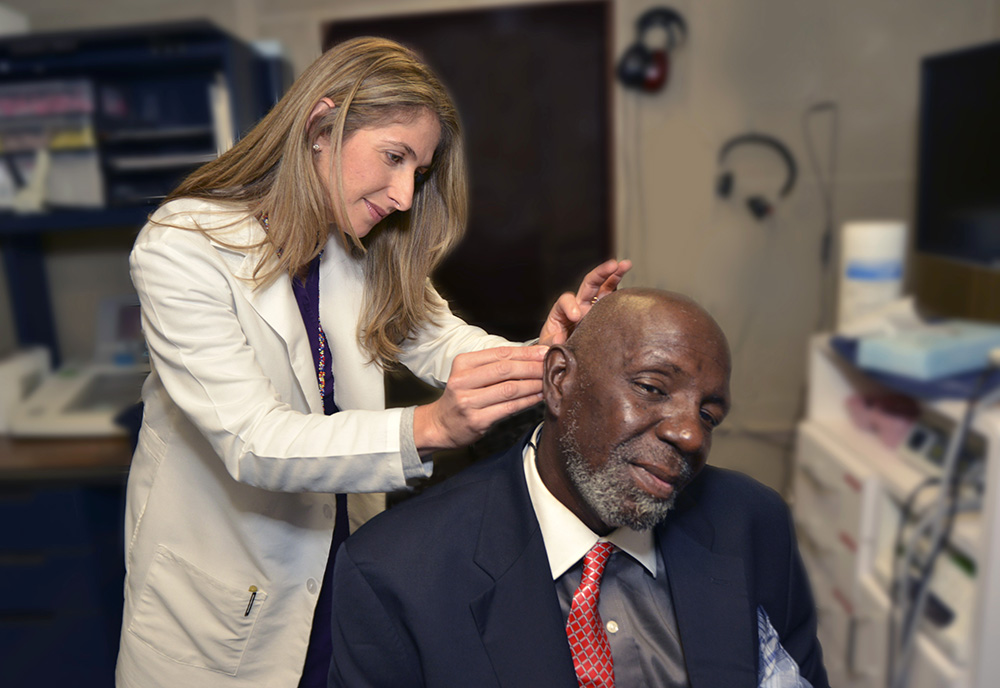 An audiologist installs a hearing aid for a Veteran patient