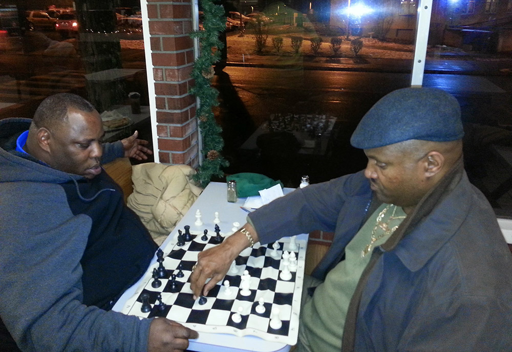 Two men play chess in a restaurant