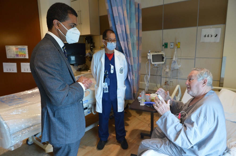 Two doctors talking to patient in hospital room.