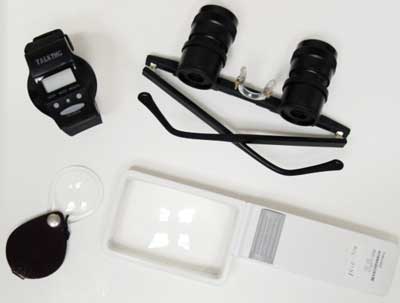 Image of low vision devices including hand held magnifiers, telescopes, and a talking watch.