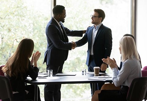 People in business attire shaking hands in a conference room. 