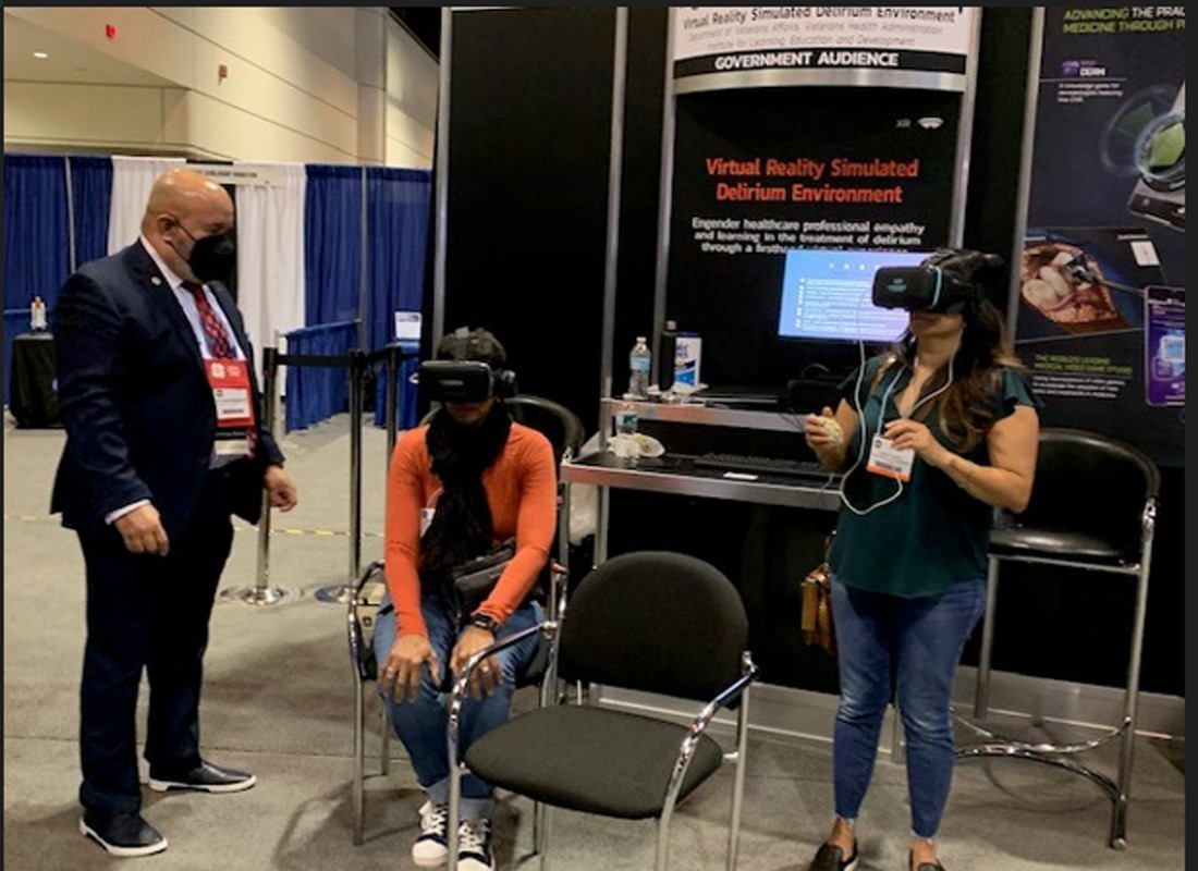 Two women trying out virtual reality headsets while a man talks them through the demonstration.
