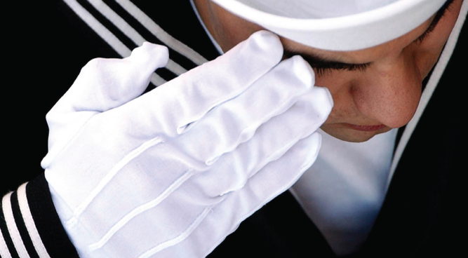 A sailor in full uniform saluting.