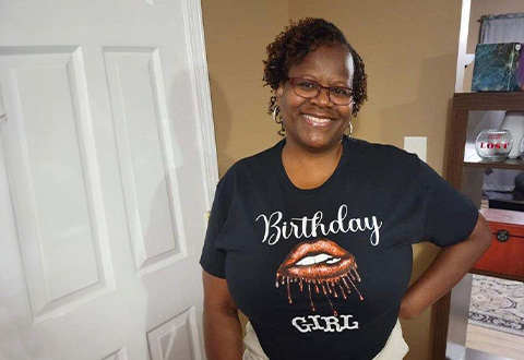 Woman standing by door in black designed graphic t-shirt that says birthday girl