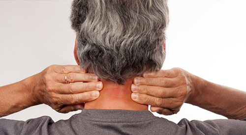 person massaging back of neck with both hands