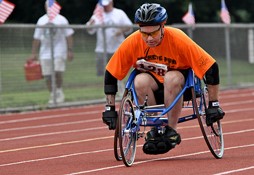 A Veteran in a wheelchair riding on a running track.