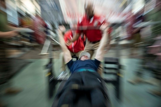 A blurred image of a Veteran bench pressing a barbell.