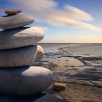 Photograph of a stack of balanced rocks by the beach.