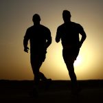 Silhouette of two men running at dusk