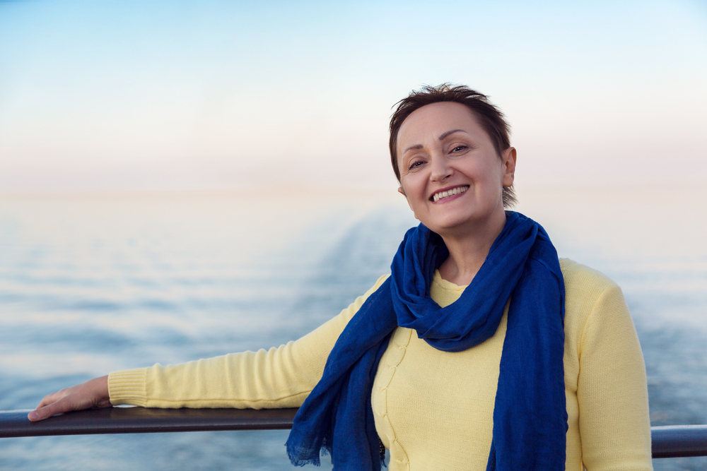 Portrait of happy woman relaxing on a luxury cruise liner boat. Beautiful sunset or sunrise blurred background.