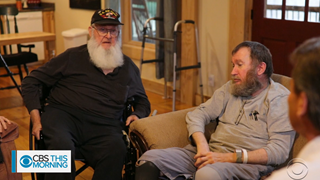 two men with beards talking in the living room