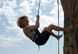 A woman clings to a rope on the side of a climbing wall