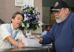 Man at a desk showing another man information on a piece of paper