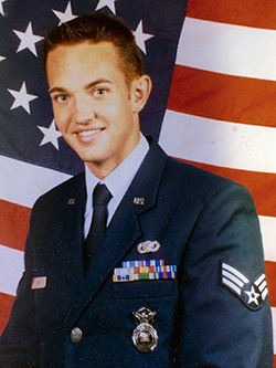 Andrew Clark in uniform sitting next to an American flag.