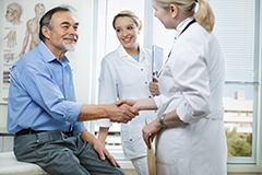 A doctor shakes the hand of a seated patient