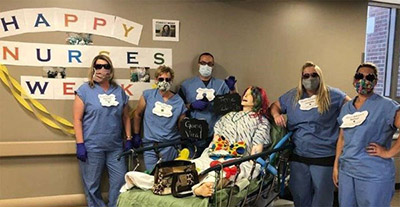 nurses in scrubs and mask around mannequin in hospital bed