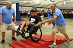 A Veteran on two wheels rolls down a stepped obstacle on the slalom course.