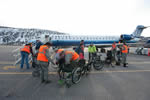 Volunteers at the Aspen/Snowmass Airport unloading wheelchairs from an airplane.