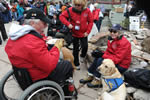 A man in a wheelchair with a guide dog eating lunch in the open air courtyard at Snowmass Village.