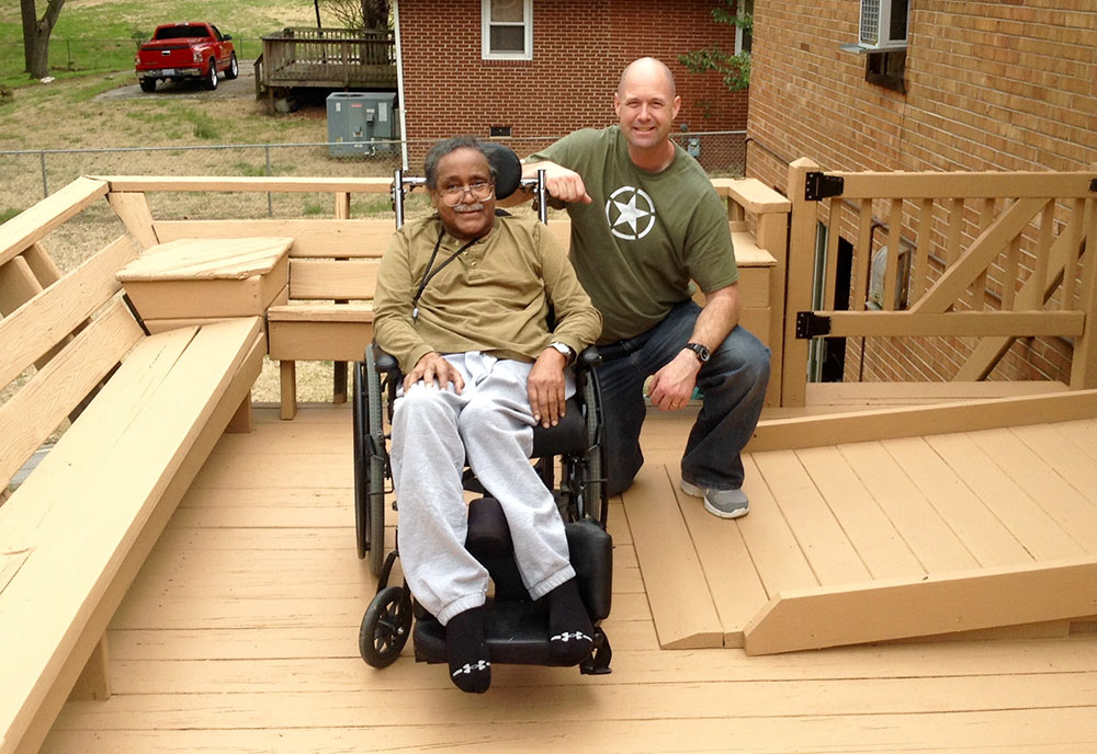 A Veteran in a wheelchair poses next to an accessible ramp to his house A Veteran in a wheelchair poses next to an accessible ramp to his house
