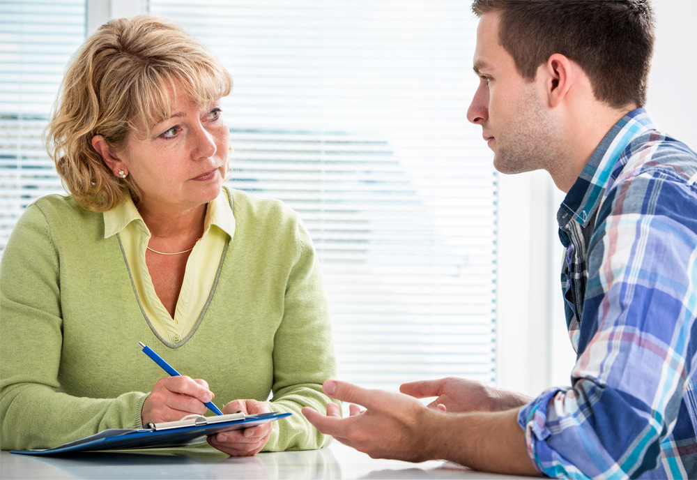 Woman with a clipboard and pen looks at a man speaking to her Woman with a clipboard and pen looks at a man speaking to her